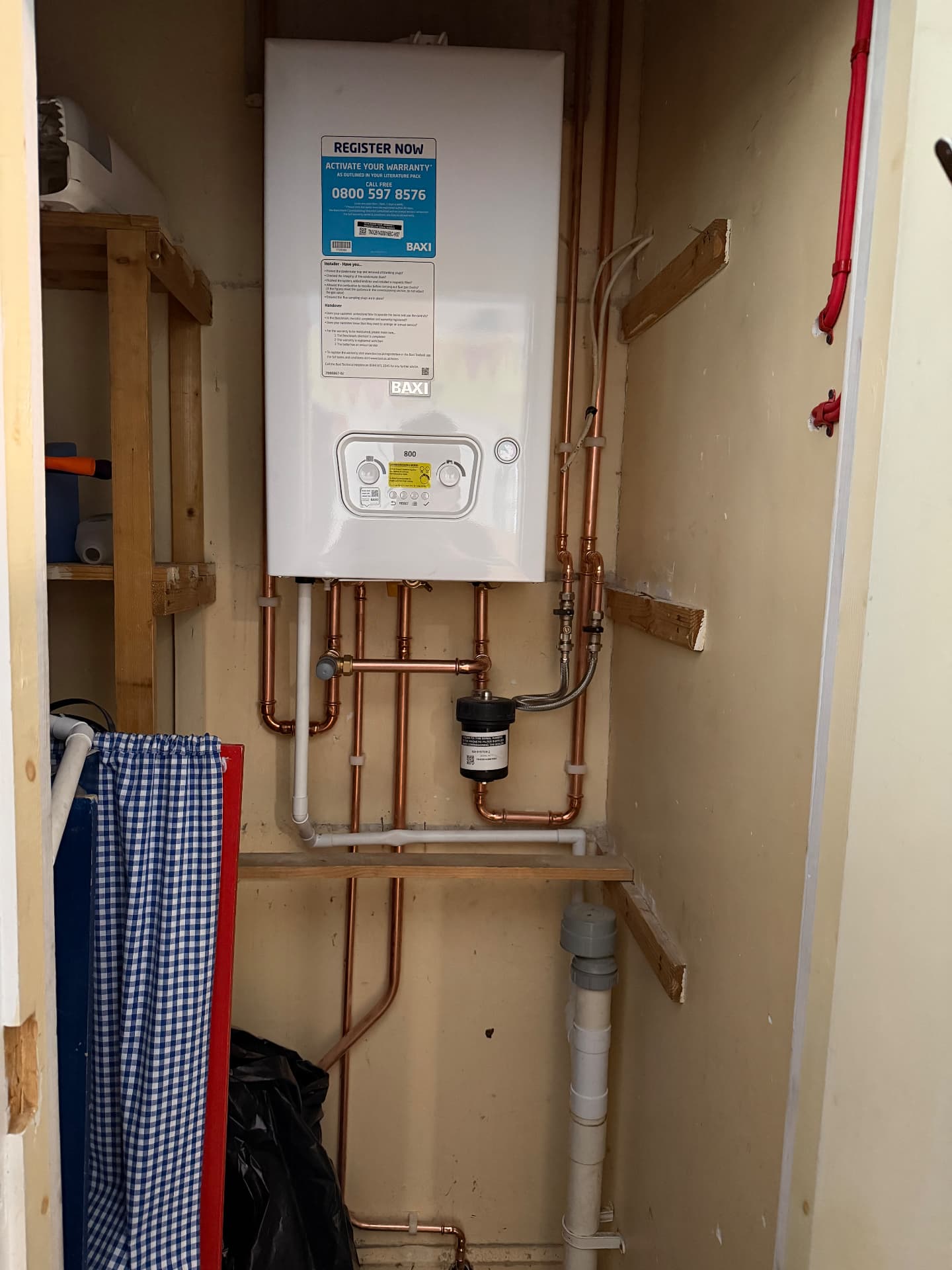 Baxi system boiler with copper pipework and magnetic filter in a storage cupboard