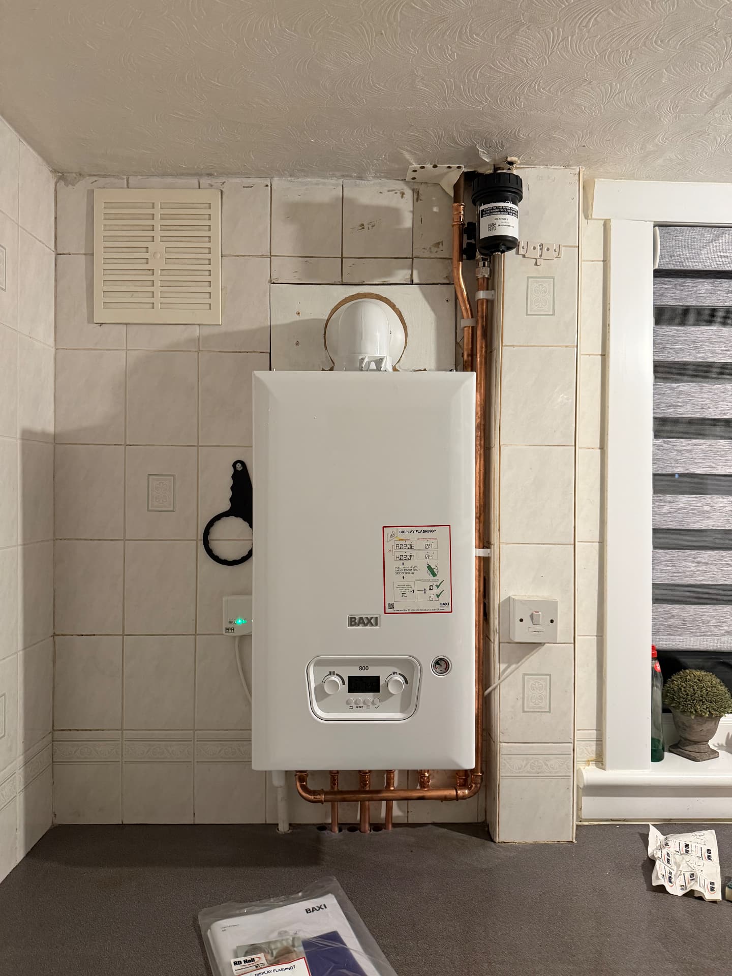 Baxi boiler installed on a tiled wall with vertical copper flow and return pipes